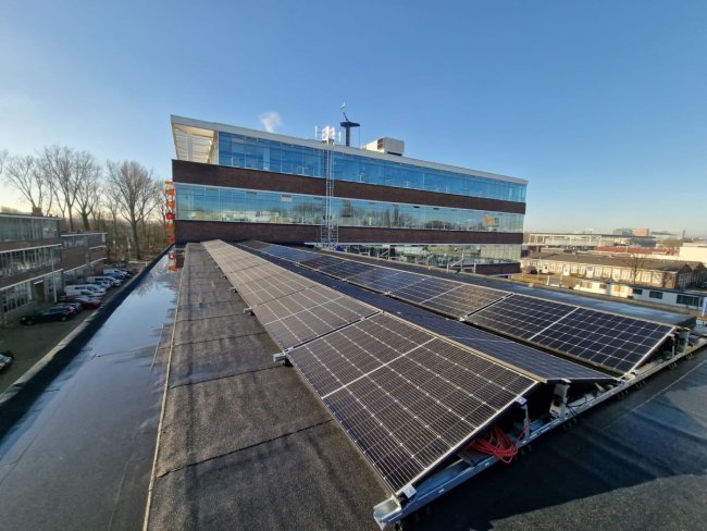 Zonnepanelen op plat dak kantoorpand blauwe lucht